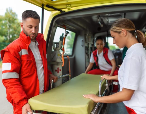 three paramedics taking out strecher from ambulance
