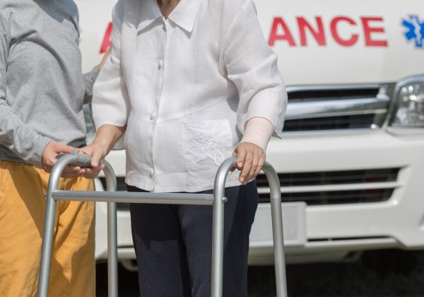 senior woman using a walker with caregiver to take ambulance
